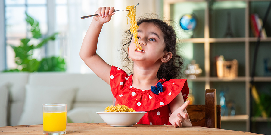 menina comendo macarrão 
